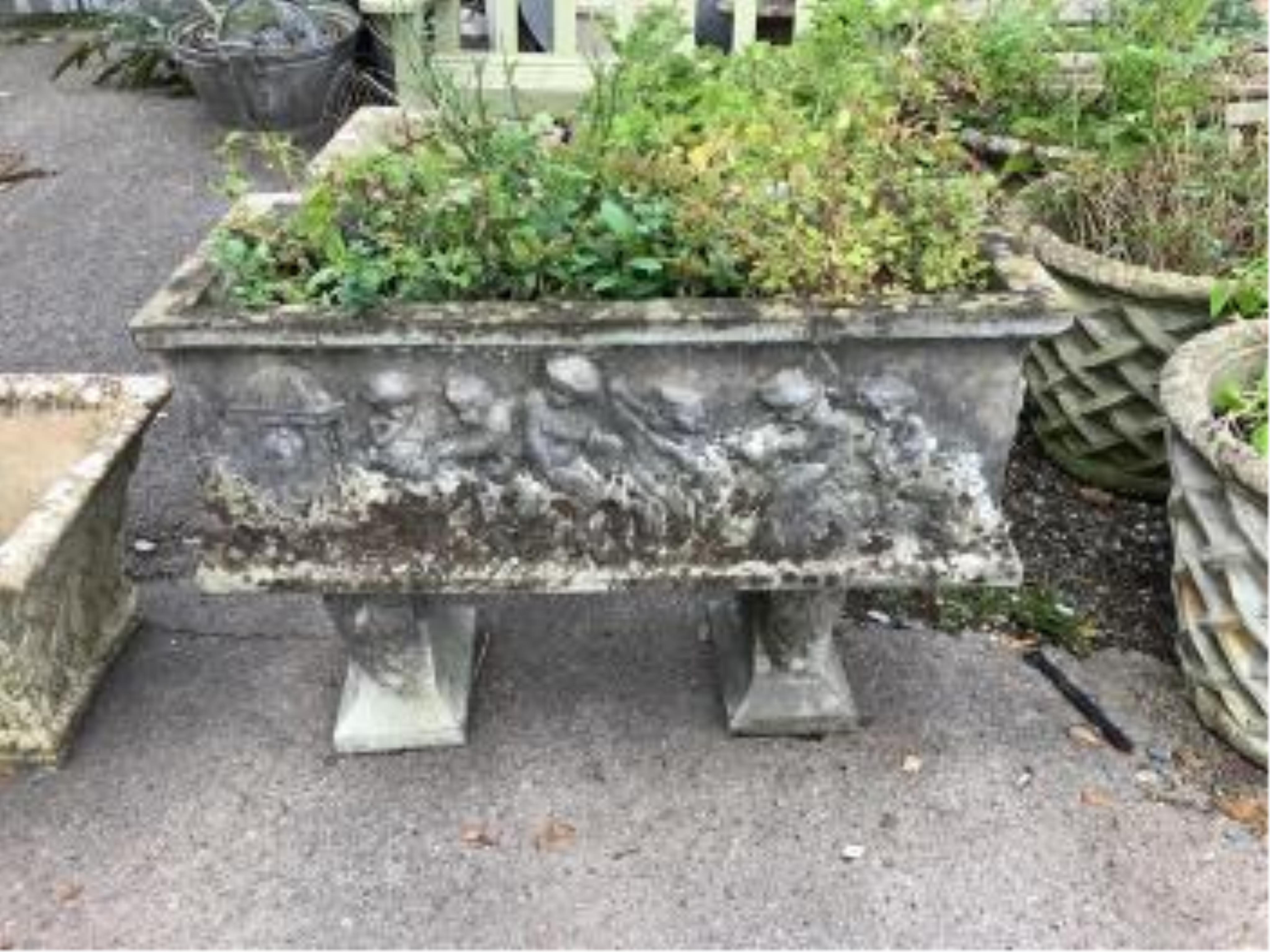 A reconstituted stone rectangular garden trough, moulded with putti, on Roman end plinths, width 89cm, depth 39cm, height 64cm. Condition - fair